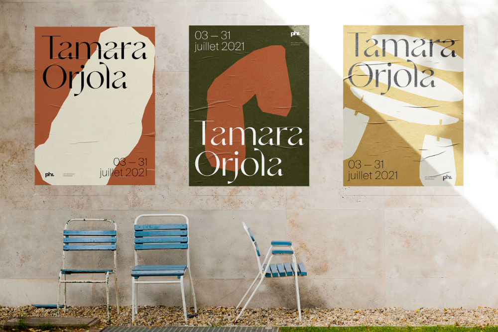 White building wall with three posters and blue chairs in front.